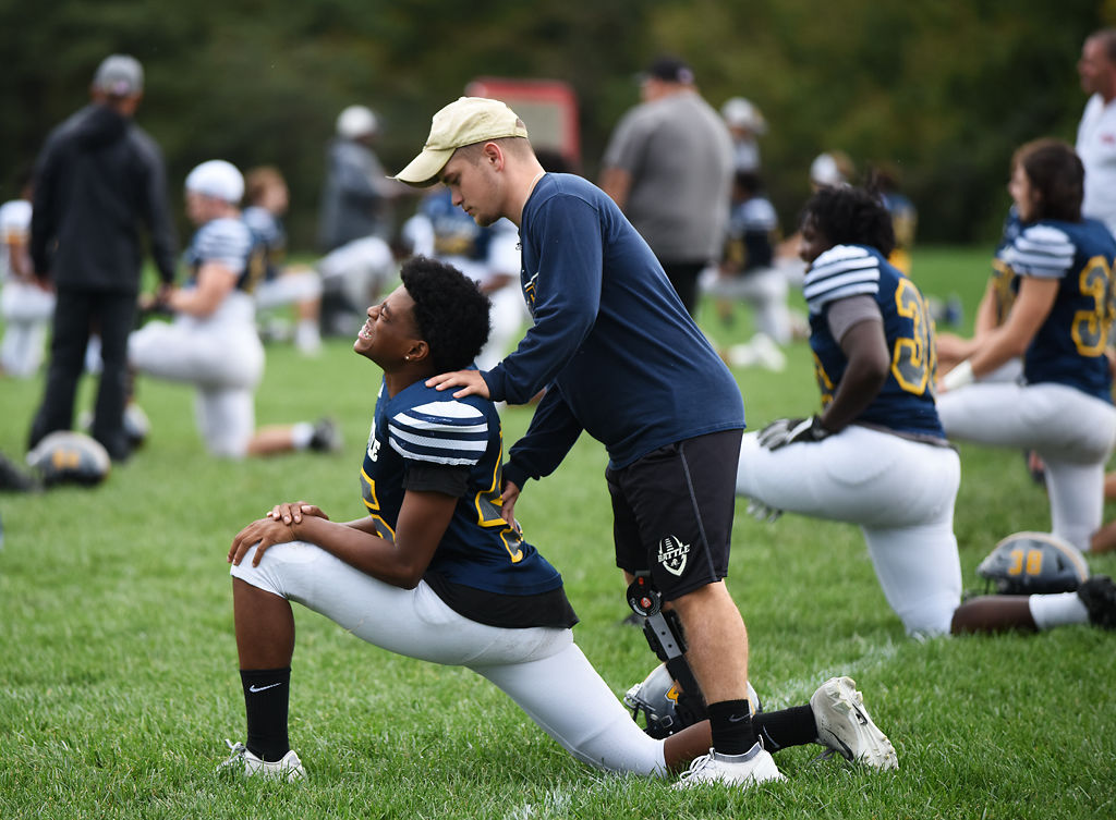 Cody Rachatellelle helps Jarrett Lambert stretch before starting practice
